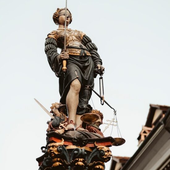 woman holding sword and balance scale statue under white sky