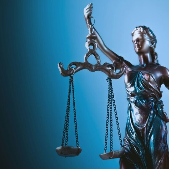Statue of justice holding scales against blue background